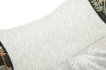 Close-up of a garment featuring a light gray fabric with a patterned edge showcasing leaves and animal prints.