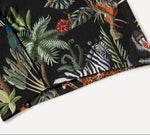 A close-up of black fabric with vibrant jungle animal and plant illustrations, featuring a zebra and tropical foliage.