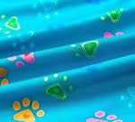 Bright blue fabric with colorful paw prints and triangular patterns. Prints in orange, pink, and green.