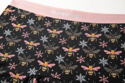 Black underwear with whimsical bee and snowflake patterns, featuring a soft pink waistband with "PureSnug" text.