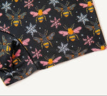 PureSnug biker shorts fabric with vibrant bees & snowflakes on black, blending nature and winter motifs.