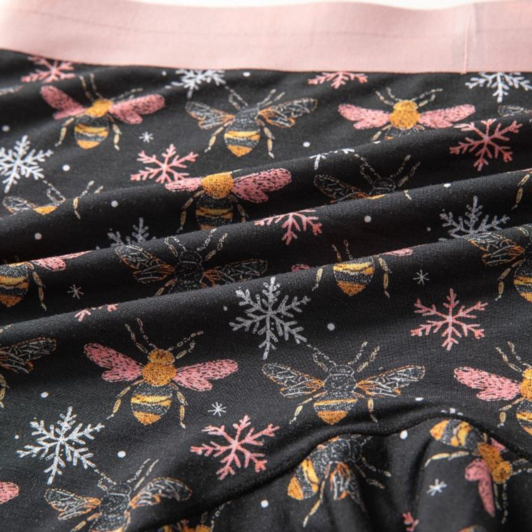 Fabric with bee and snowflake pattern on black background