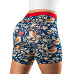 Close-up of patterned shorts featuring birds and strawberries, with a red waistband, worn by a person from the back.