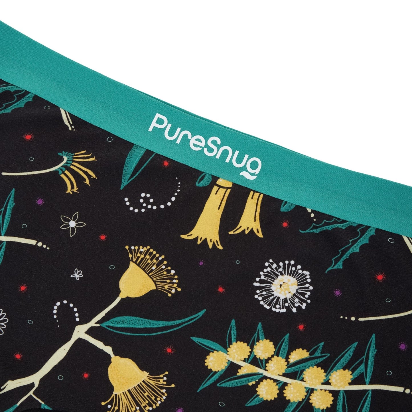 Close-up of a fabric edge with vibrant botanical prints on a black base, finished with a teal waistband