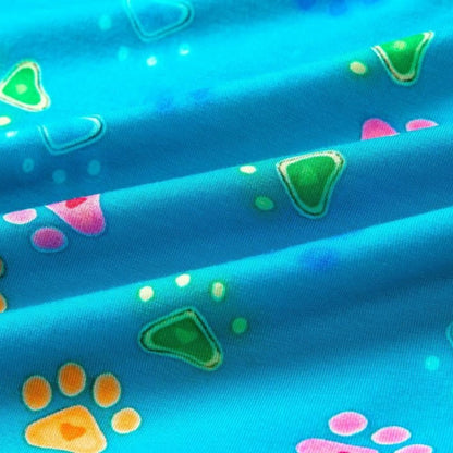 Close-up of vibrant blue fabric featuring colorful paw prints and geometric shapes in pink, green, and orange patterns.