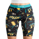 A model wearing black patterned biker shorts featuring colorful floral designs and a turquoise PureSnug waistband.