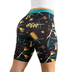 A woman wearing fitted black biker shorts with a colorful floral pattern and a turquoise waistband, showcasing a stylish athletic look.