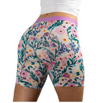 Woman wearing floral-patterned PureSnug boxer briefs with vibrant pink, purple, and green design
