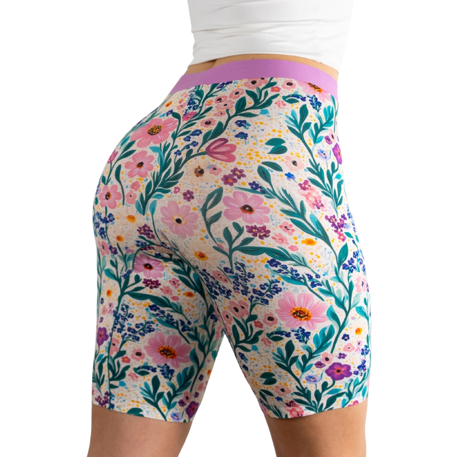 Model wearing colorful floral print biker shorts with a purple waistband, showcasing a vibrant, nature-inspired design.