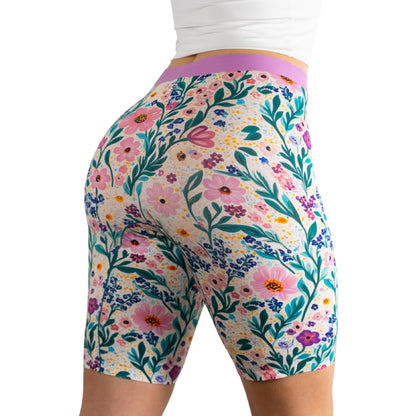 Model wearing colorful floral print biker shorts with a purple waistband, showcasing a vibrant, nature-inspired design.