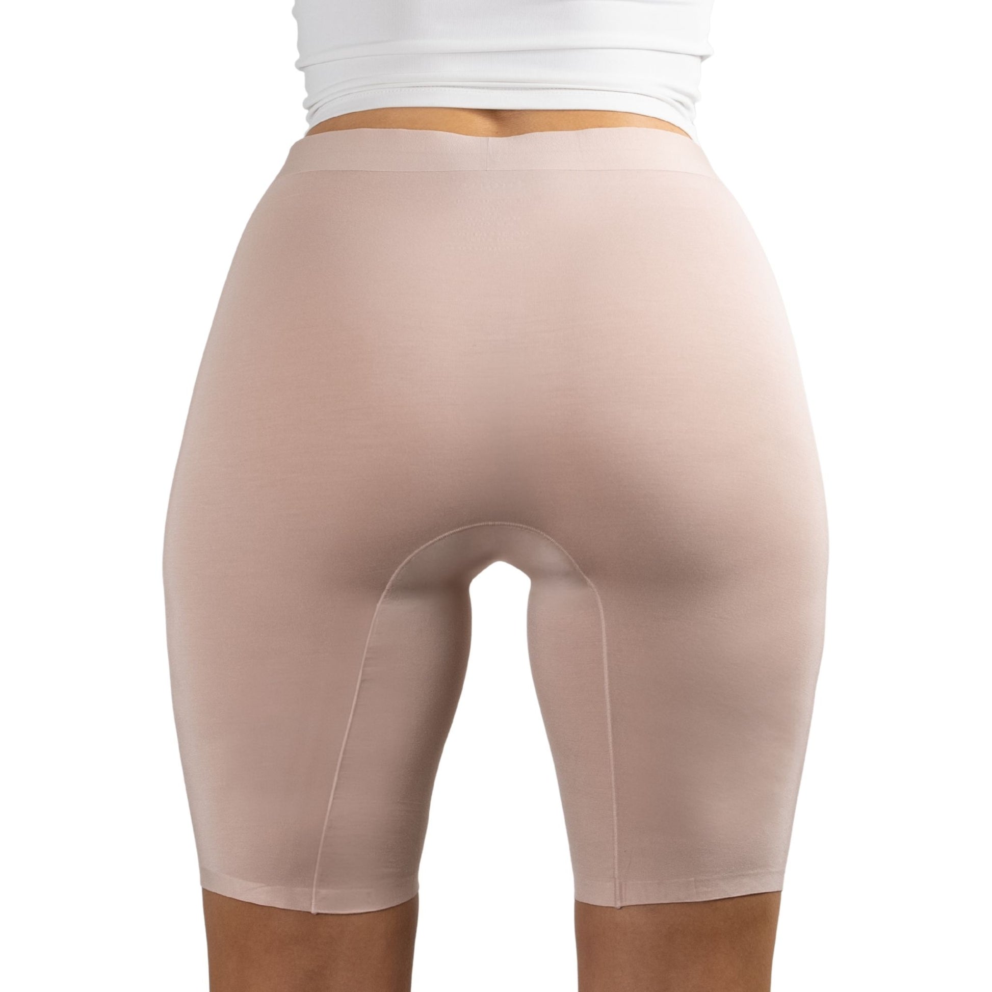 Back view of a woman wearing PureSnug's High-waisted Blush Beige nude-colored seamless biker shorts and a white top.