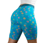 A model wearing PreSnug's hiugh-waisted biker shorts with colorful paw prints in pink, orange, green, and blue.