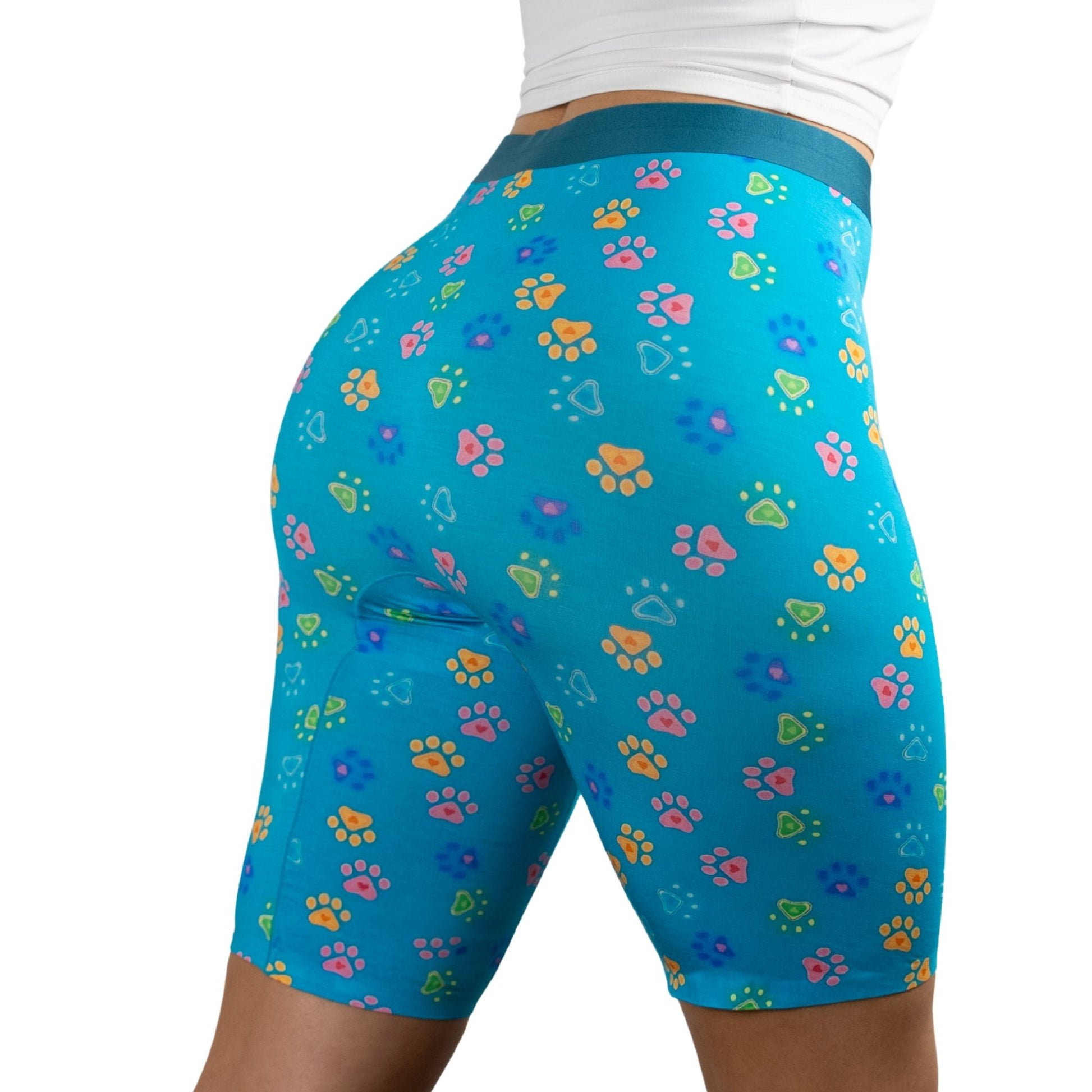 A model wearing PreSnug's hiugh-waisted biker shorts with colorful paw prints in pink, orange, green, and blue.