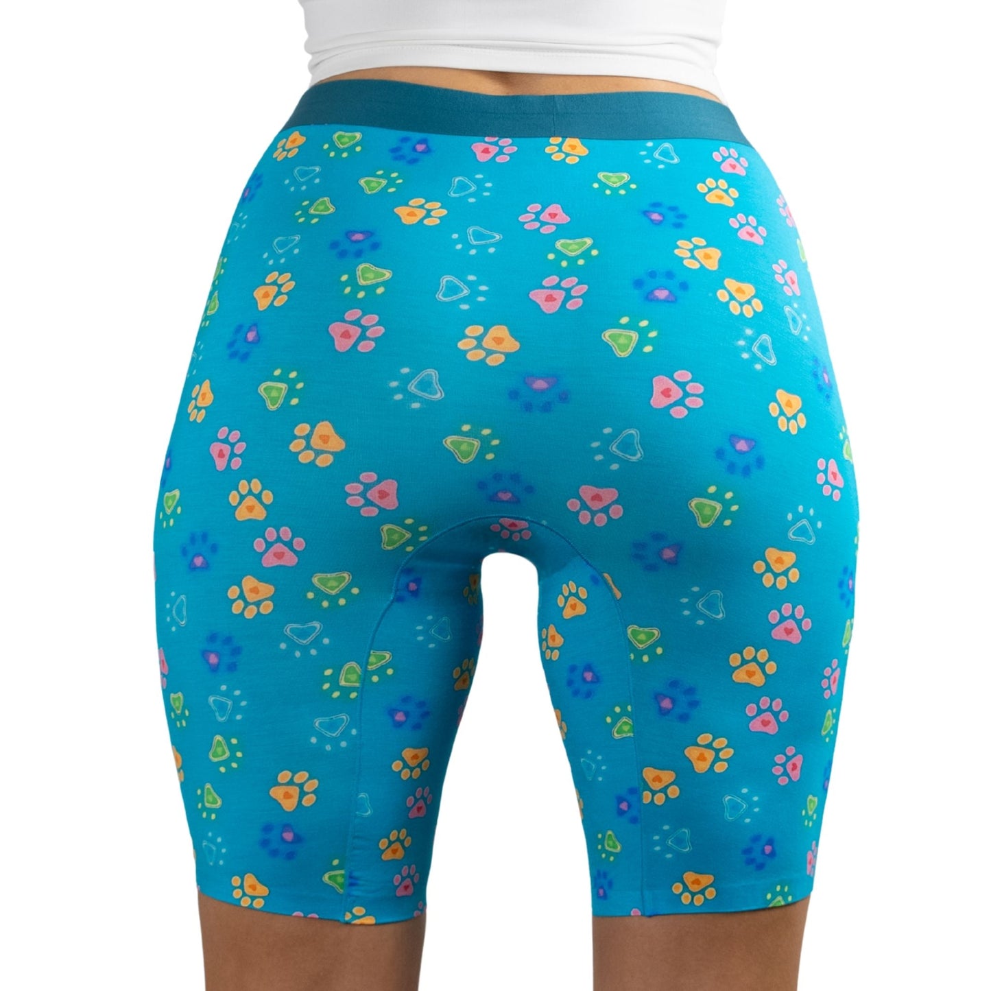 A model wearing PureSnug's High-waisted biker shorts with colorful paw prints and heart designs.