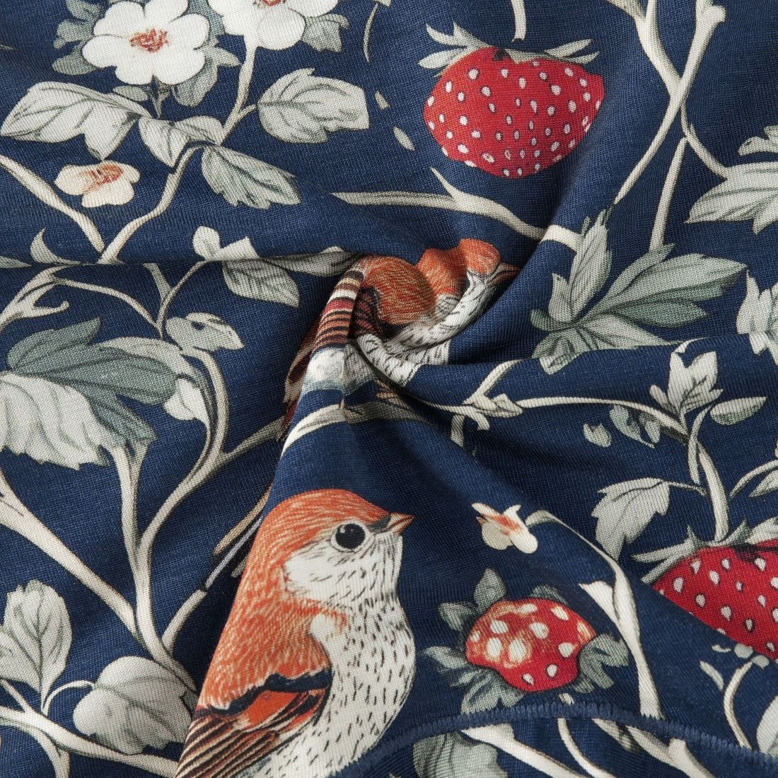 Fabric with a pattern of birds, flowers, and strawberries on a blue background