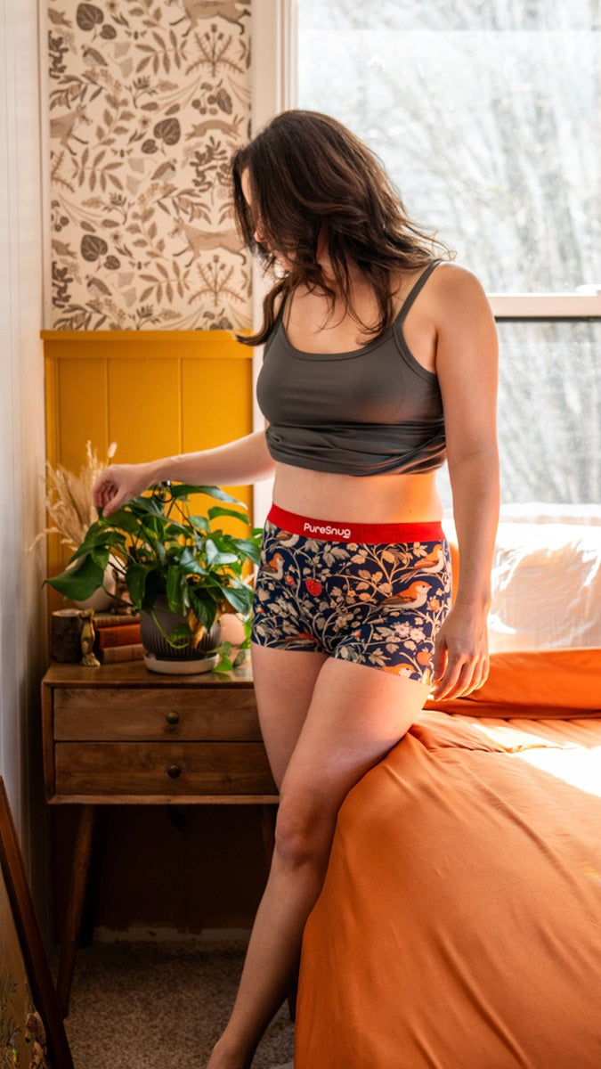 Woman wearing a sports bra and Pure Snug underwear in a bedroom.