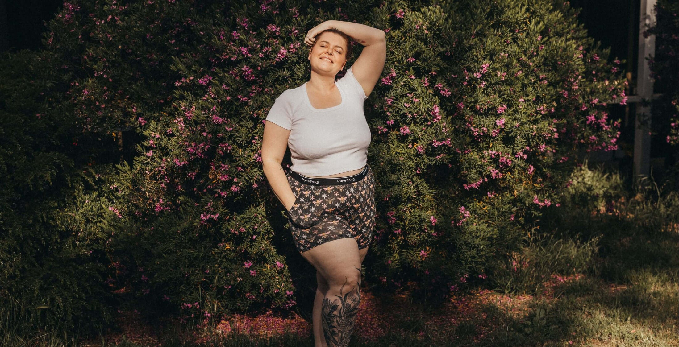 Woman standing outdoors with greenery and flowers in the background wearing Pure Snug loungewear