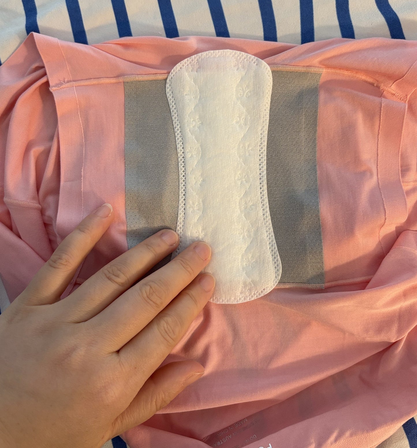 demenstrating a white sanitary pad smoothly stick to the grey gusset of Pure Snug underwear 